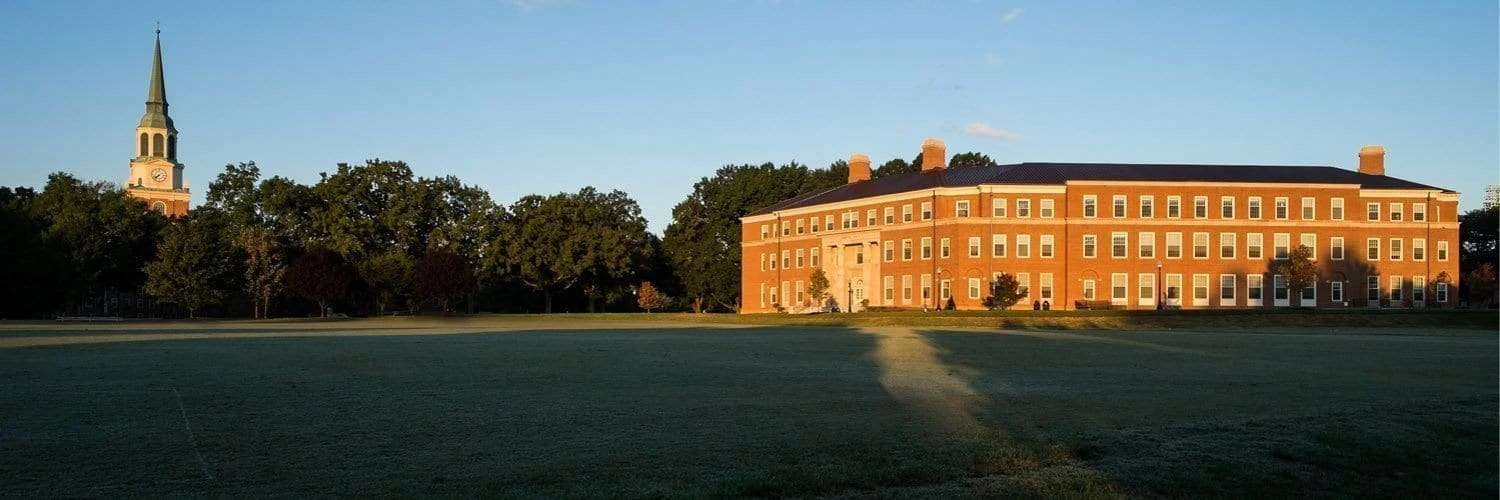 Farrell Hall in warm evening light with Wait Chapel visible beyond the trees